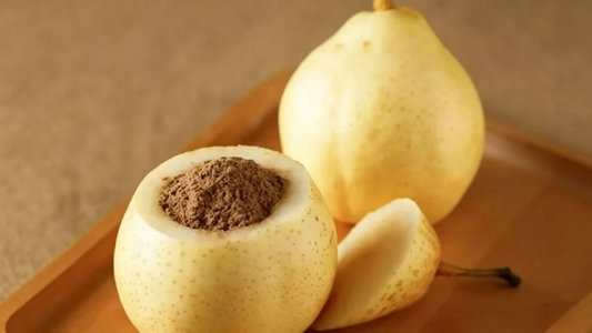 Traditional Chinese pear remedy: a hollowed pear filled with brown medicinal powder, paired with whole pears on a wooden tray
