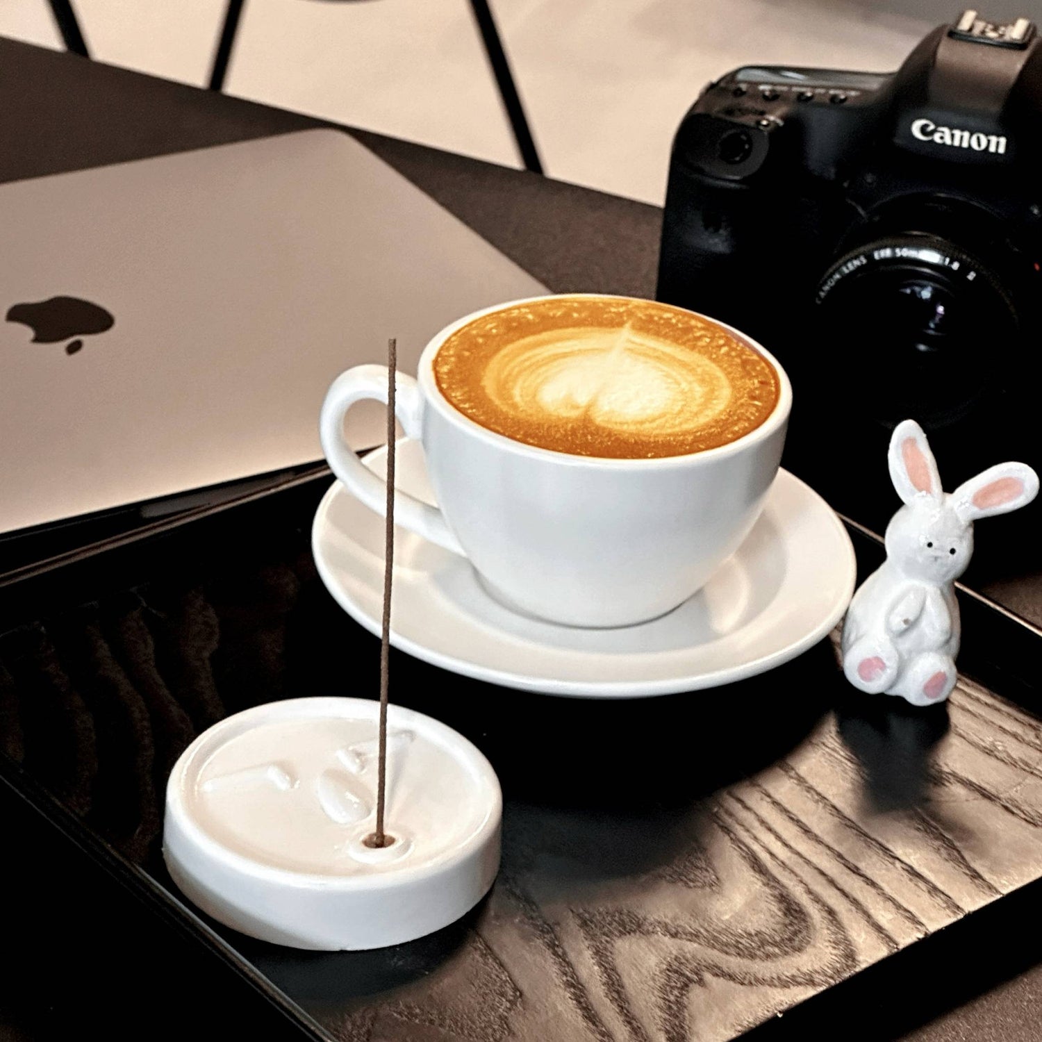 Handcrafted ceramic incense holder with natural incense stick, styled with coffee latte, laptop, and camera in a cozy home office setup.

