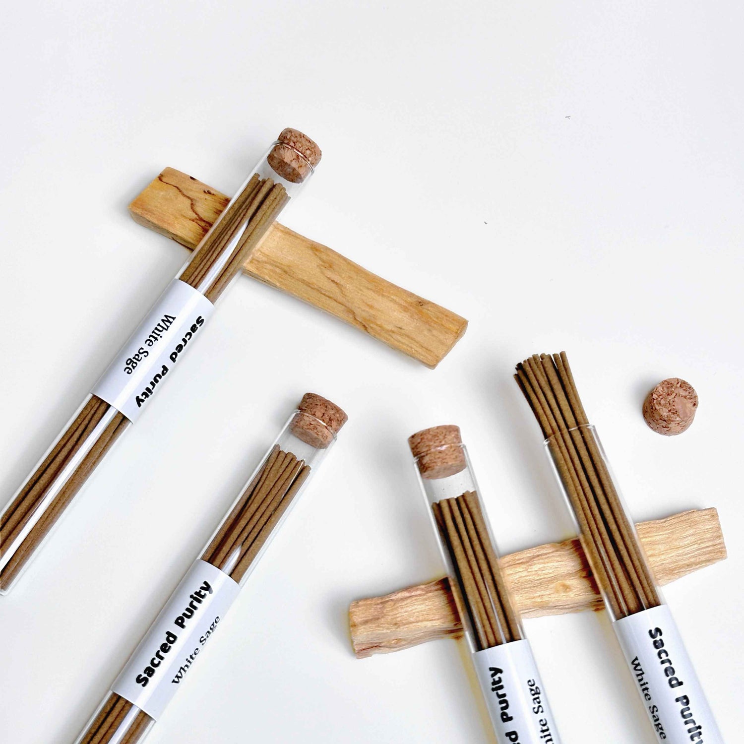 Premium Sacred Purity White Sage natural incense sticks in glass cork tubes, styled on wooden cross stands, handcrafted aromatherapy for space cleansing, meditation and spiritual wellness.